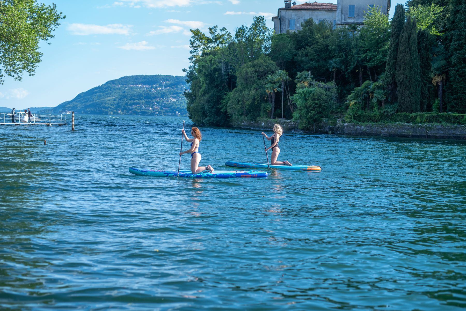 Zwei Stand-up-Paddler auf dem See vor einer alten Villa