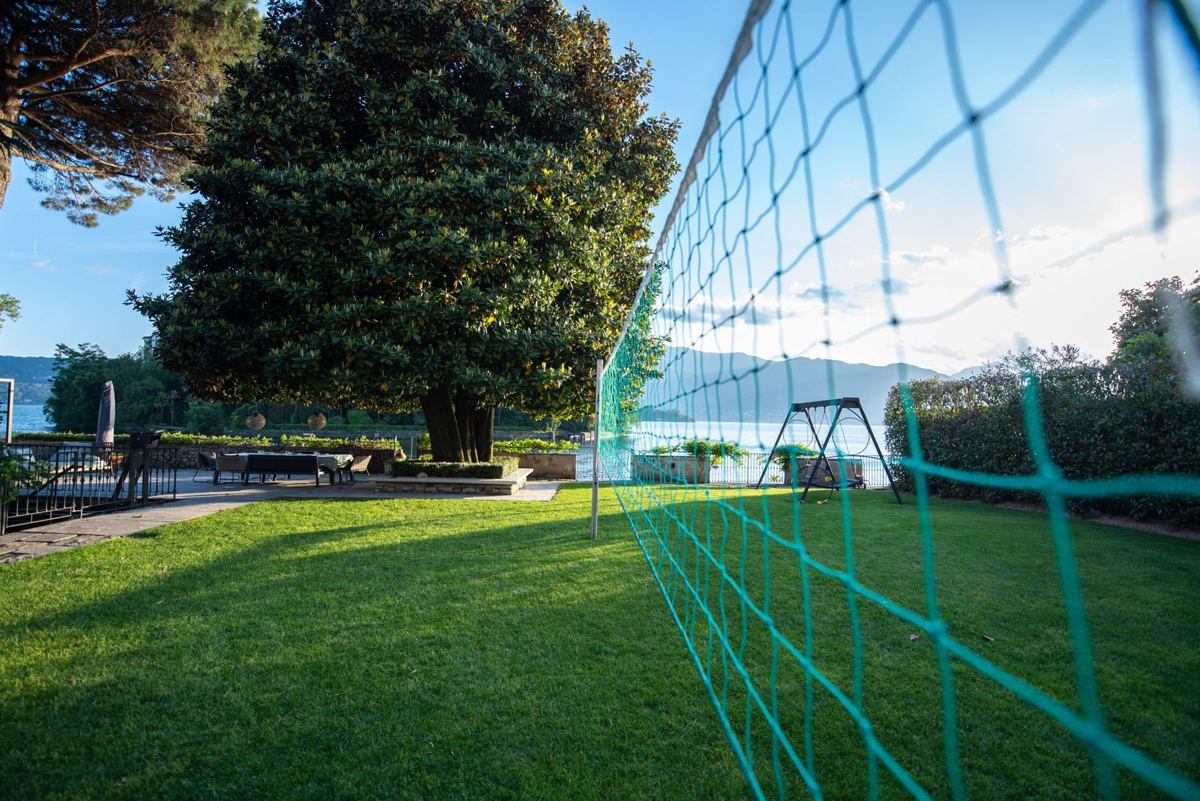 Volleyballnetz auf dem Rasen, dahinter Magnolie und See