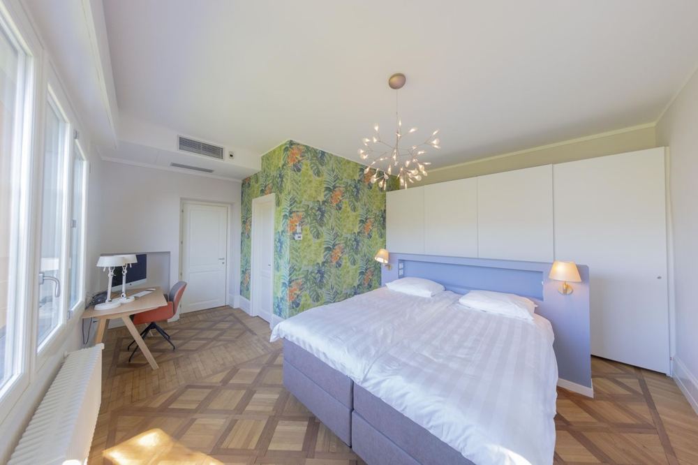 Bedroom with jungle wallpaper, desk and glass front