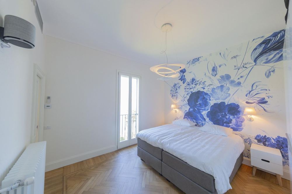 Bedroom with blue floral wallpaper and balcony door