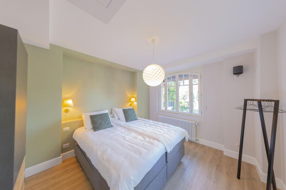 Bedroom with a sage-green wall and arched window to the garden