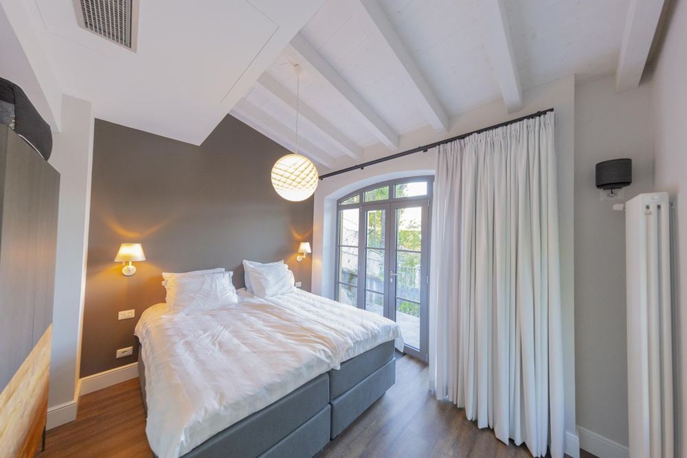 Bedroom with white wooden beams and balcony door